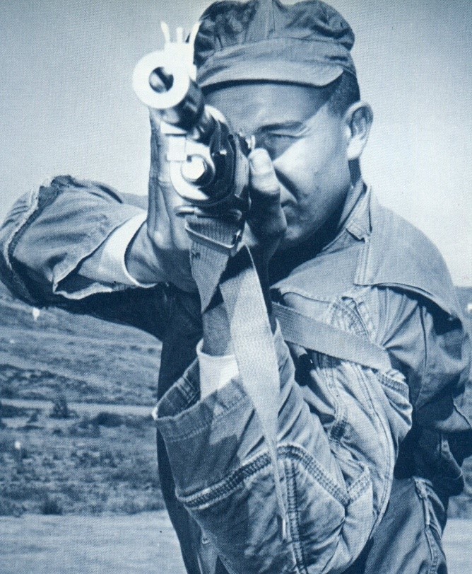 Historical photo of Marin pointing rifle at camera